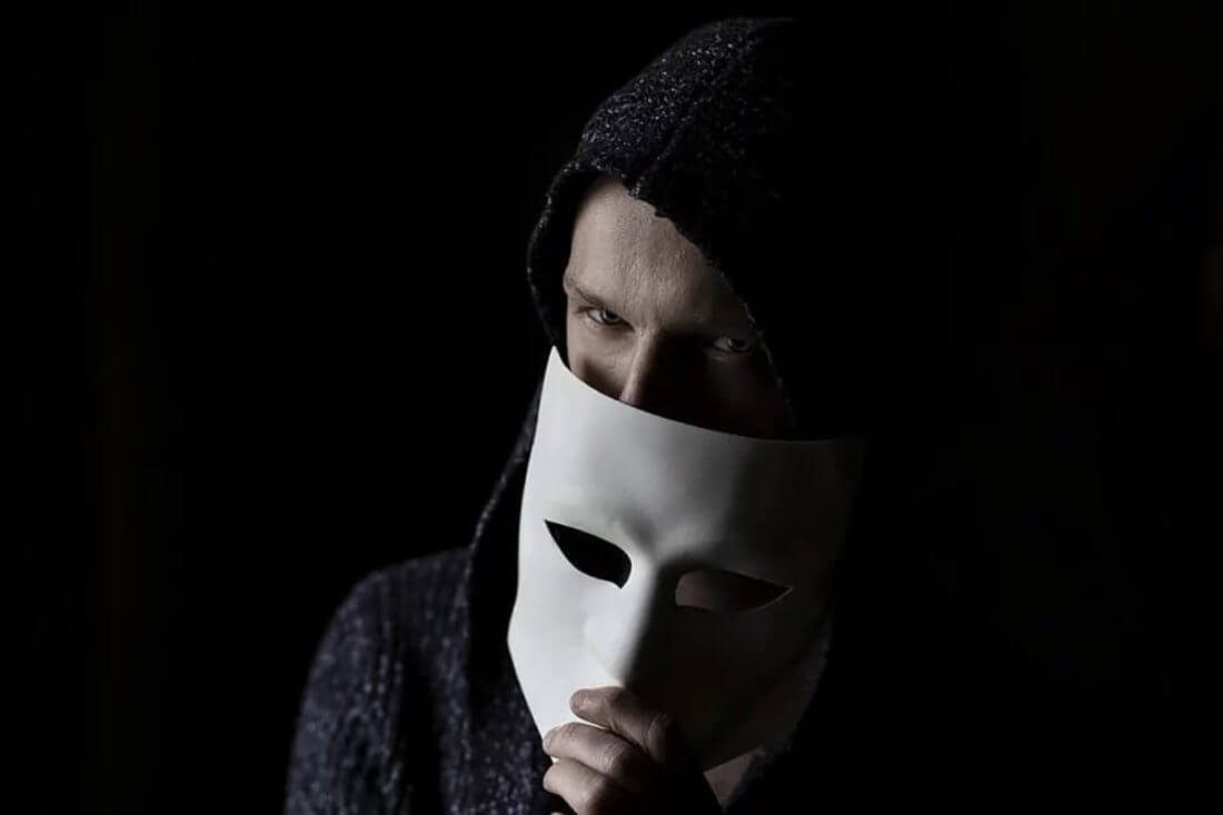 A man in a hoodie holding a mask
