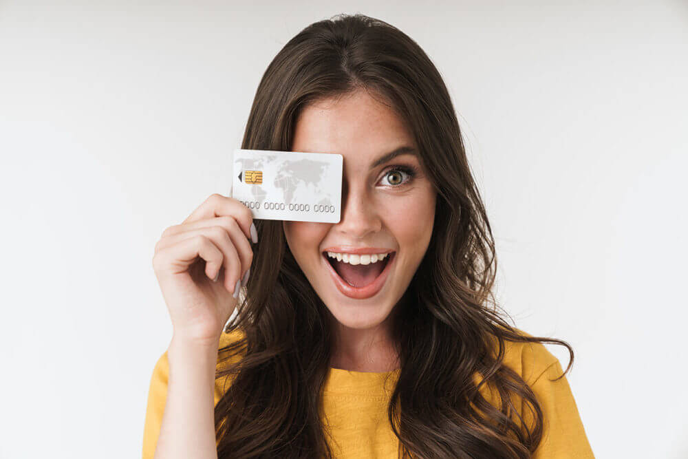 A girl smiling and holding a credit card