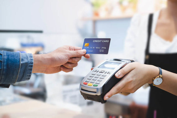 A person off-screen paying with a credit card