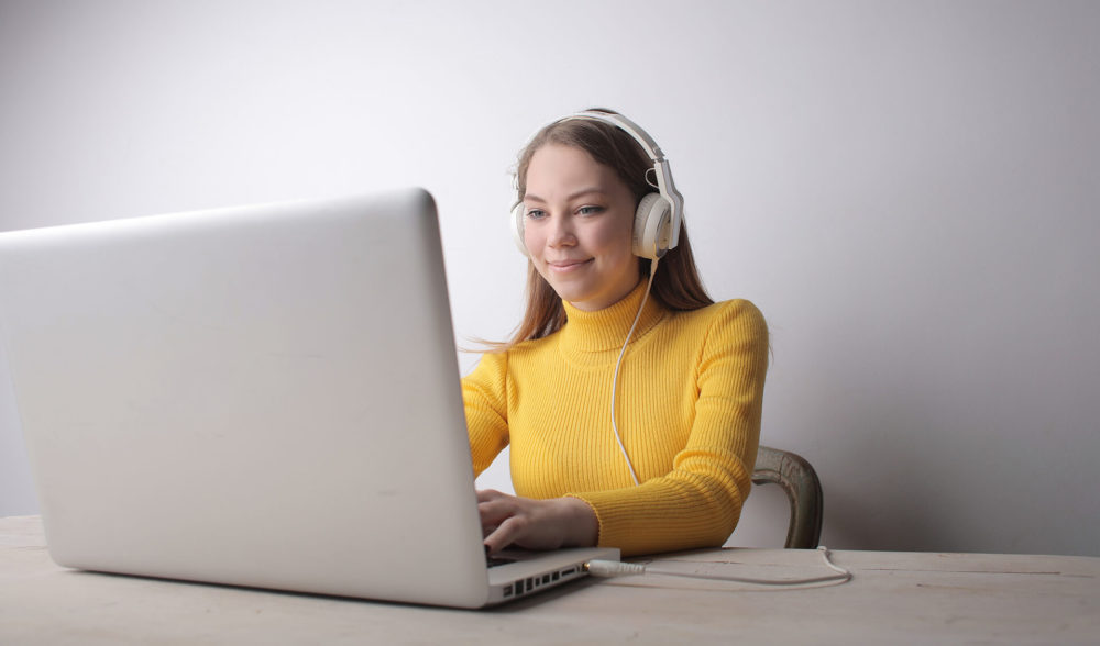 A woman with headphones working on a laptop