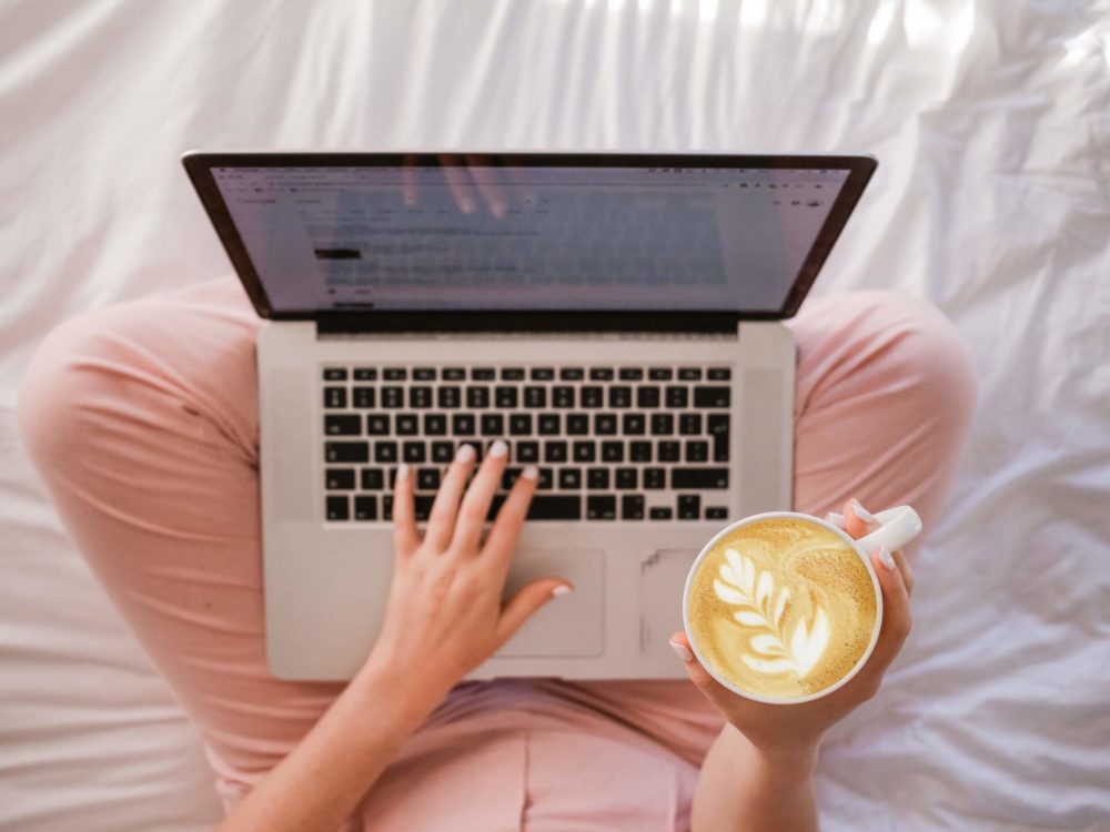 Woman holding a laptop in her lap and a cup of coffee