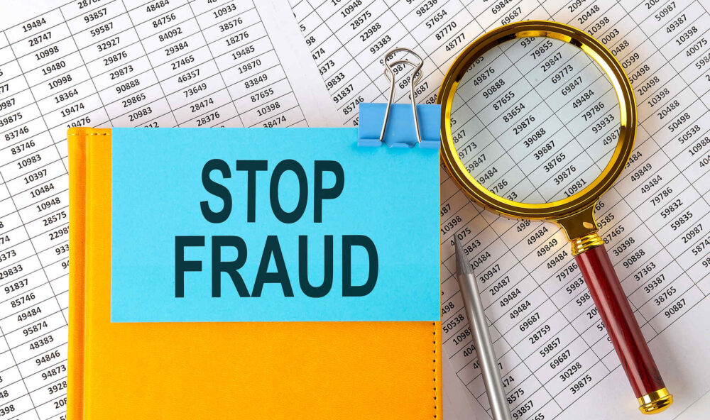 STOP FRAUD text on a sticker on a notebook with a magnifier and chart