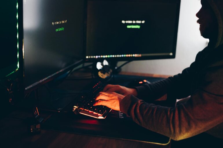 A man typing on a computer keyboard while hacking a system